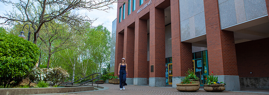student walking in front of Ames Library
