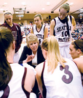 SPU women basekball players and their coach strategize.