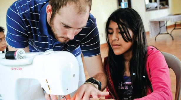 SPU senior Christifer Tomoson helped this girl learn to use a sewing machine.