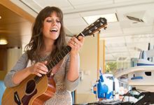 An SPU music therapy alum plays her guitar in a hospital.