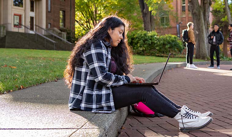 An SPU student works on their laptop in Tiffany Loop