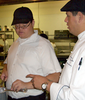 Dan Escobar '04, program development manager for Kitchens With Mission, works with a student. 